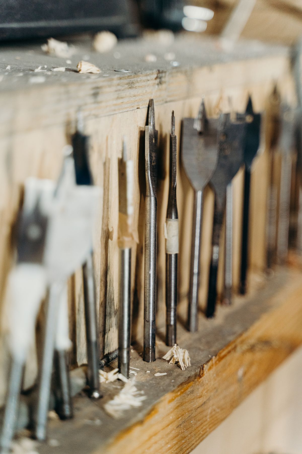Woodworking drill bits stored upright on a timber shelf